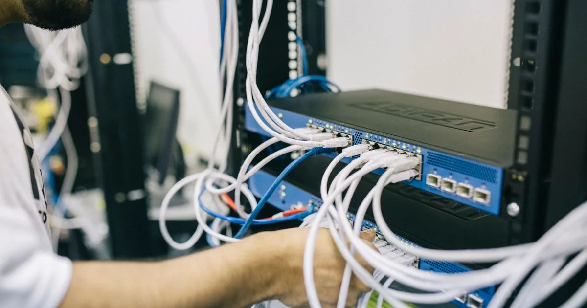 An engineer working on connections in a network equipment rack