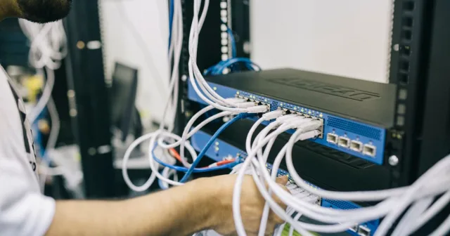 An engineer working on connections in a network equipment rack