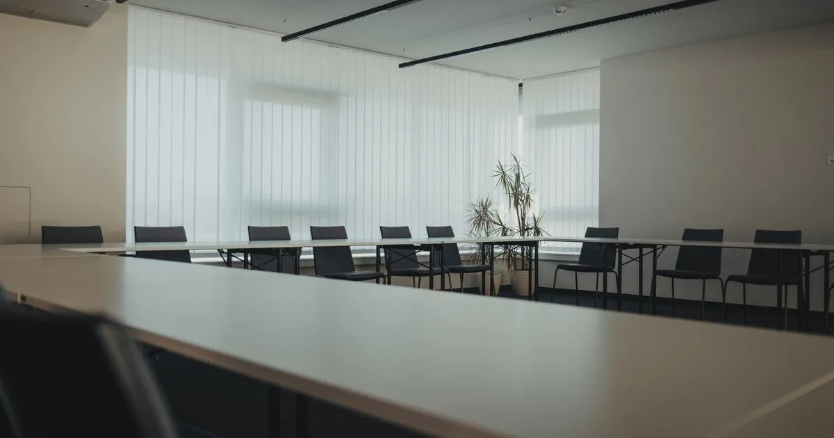 An empty modern office meeting room with large windows and a long table